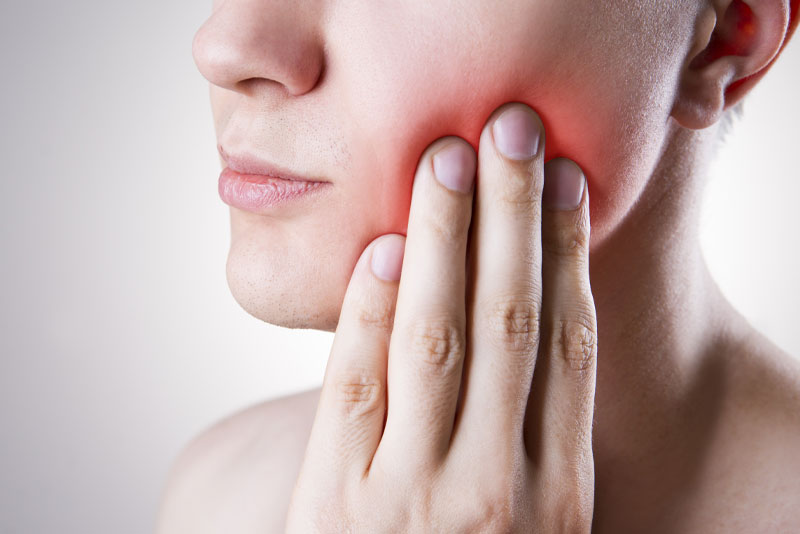 image of a woman whose hand is on hurting jaw and is in need of jaw surgery