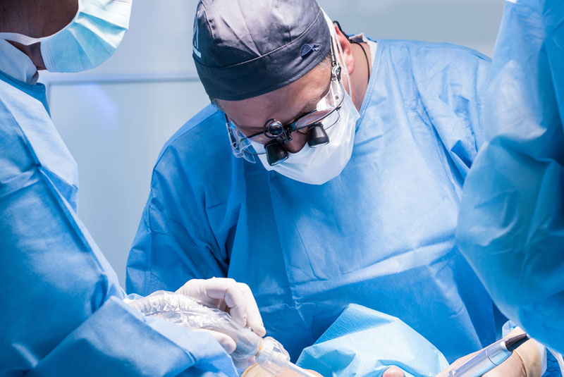 an oral surgeon performing a procedure on a patient with his team of professionals