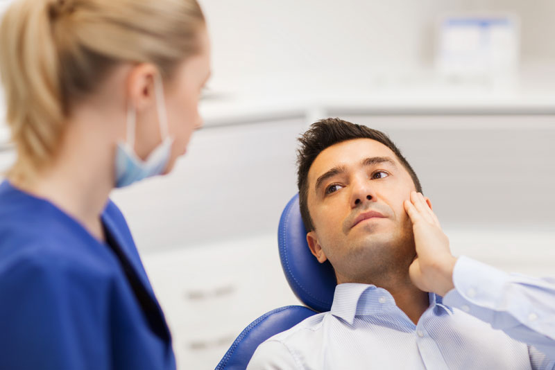a patient with a painful wisdom tooth talking to an oral surgeon about a wisdom tooth removal.
