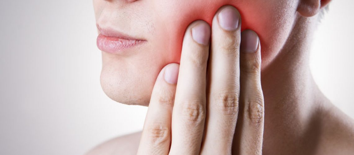 image of a woman whose hand is on hurting jaw and is in need of jaw surgery