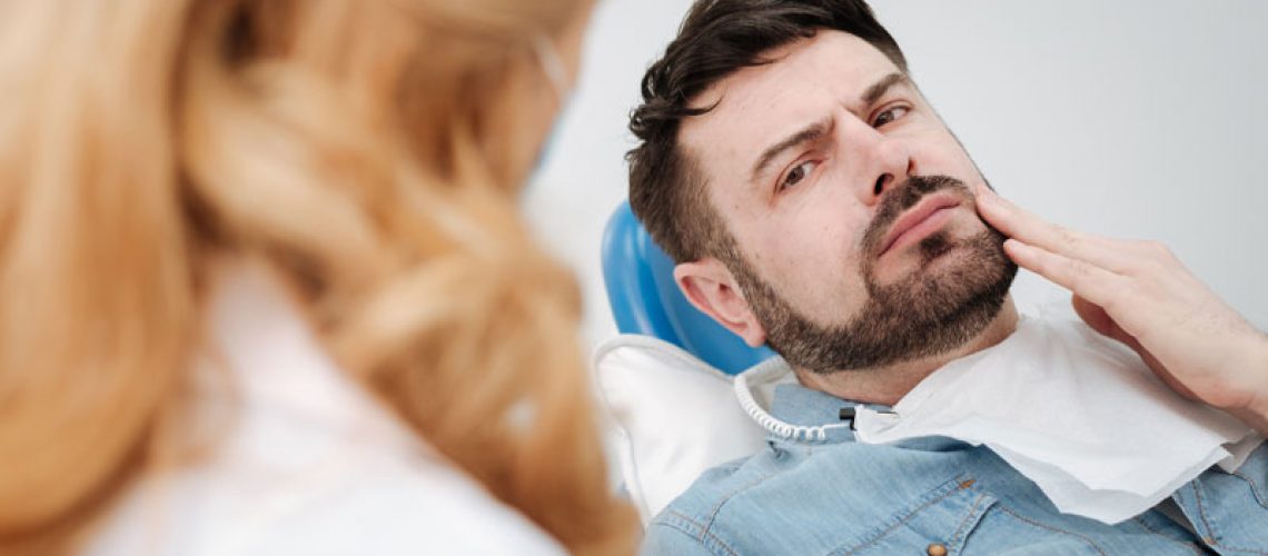 a dental patient frustrated by a painful impacted wisdom tooth